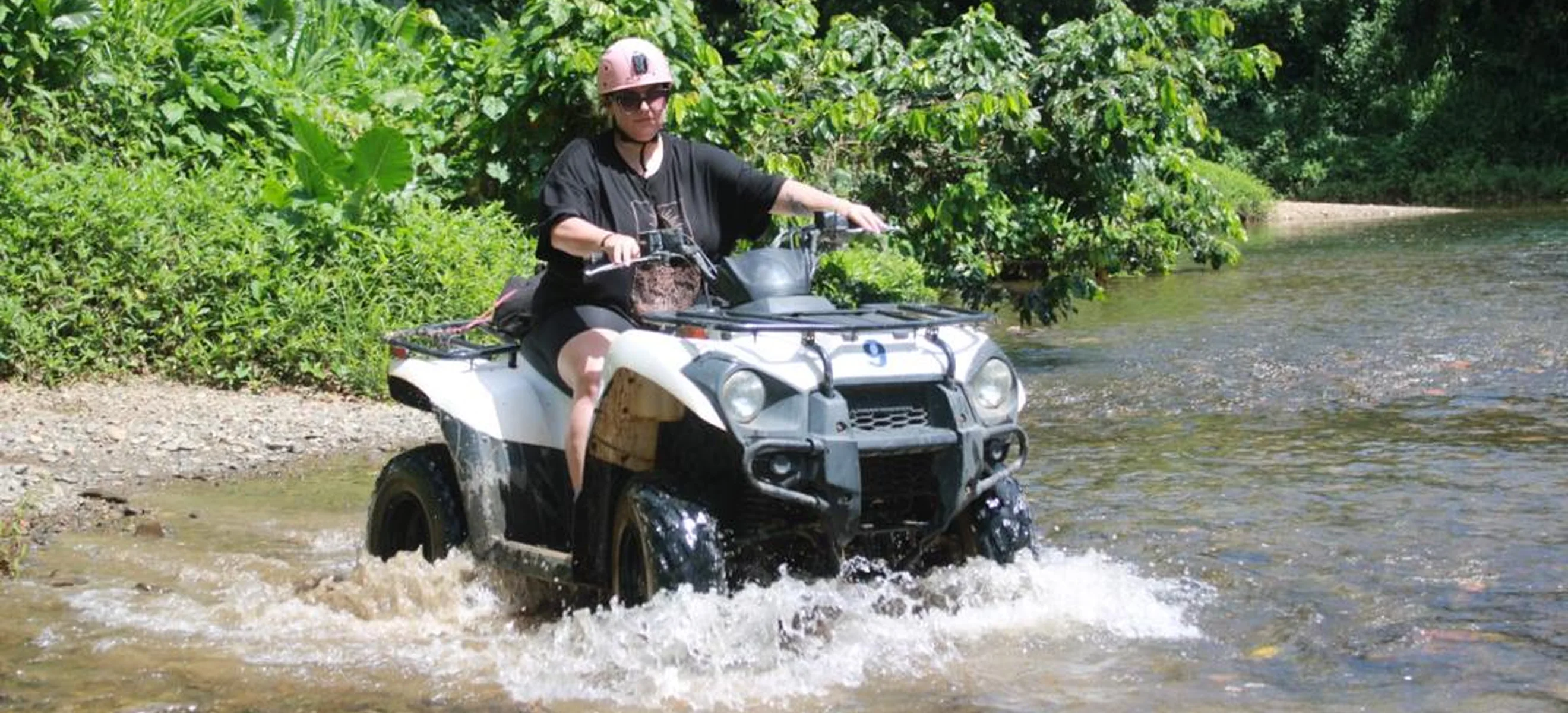 ATV rider crossing a tropical river on a Punta Cana off-road excursion.